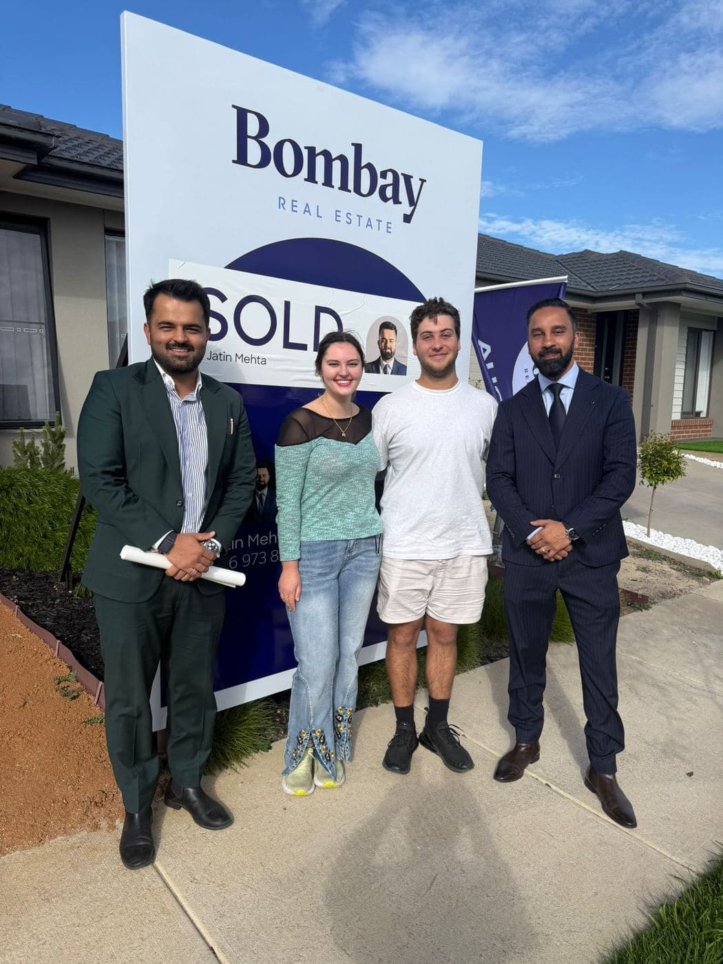 Buyers with the team beside a sold board on settlement day