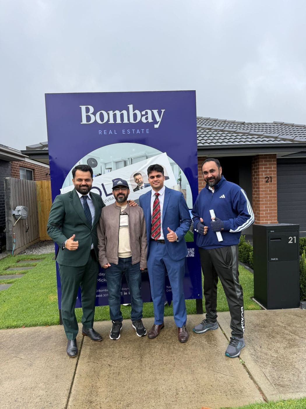 The sales team with a family in front of a sold board