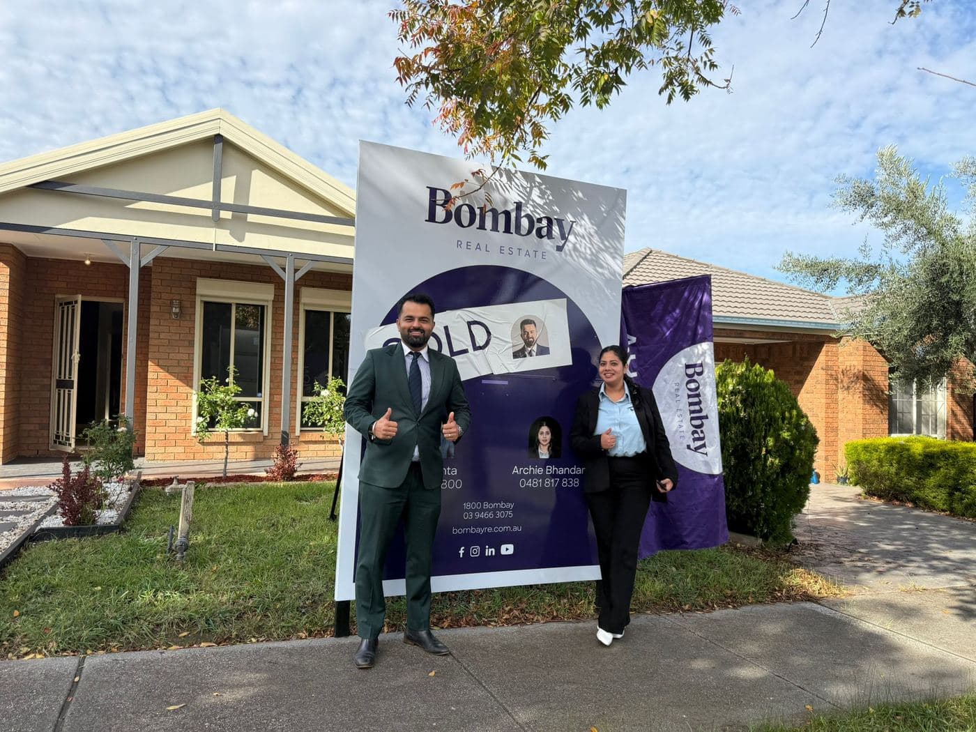 Sold and auction signage outside a brick home